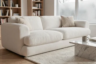 Canapé nuage blanc moelleux dans un salon cocooning style scandinave avec tapis boucle ivoire et table basse en marbre