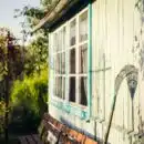 garden rake leaning on white wooden wall at daytime